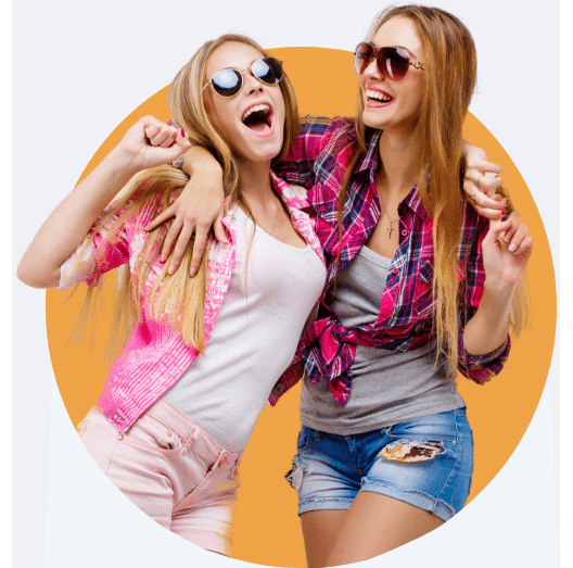 Two teenage girls in sunglasses and bright clothes, dancing together after receiving Invisalign teen from their Modesto orthodontist